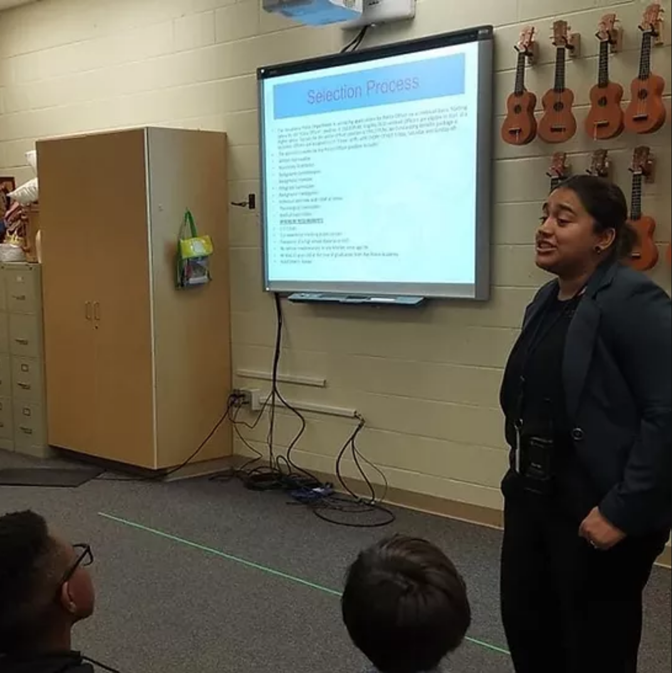 Keith stands at the front of a classroom, presenting from a digital screen