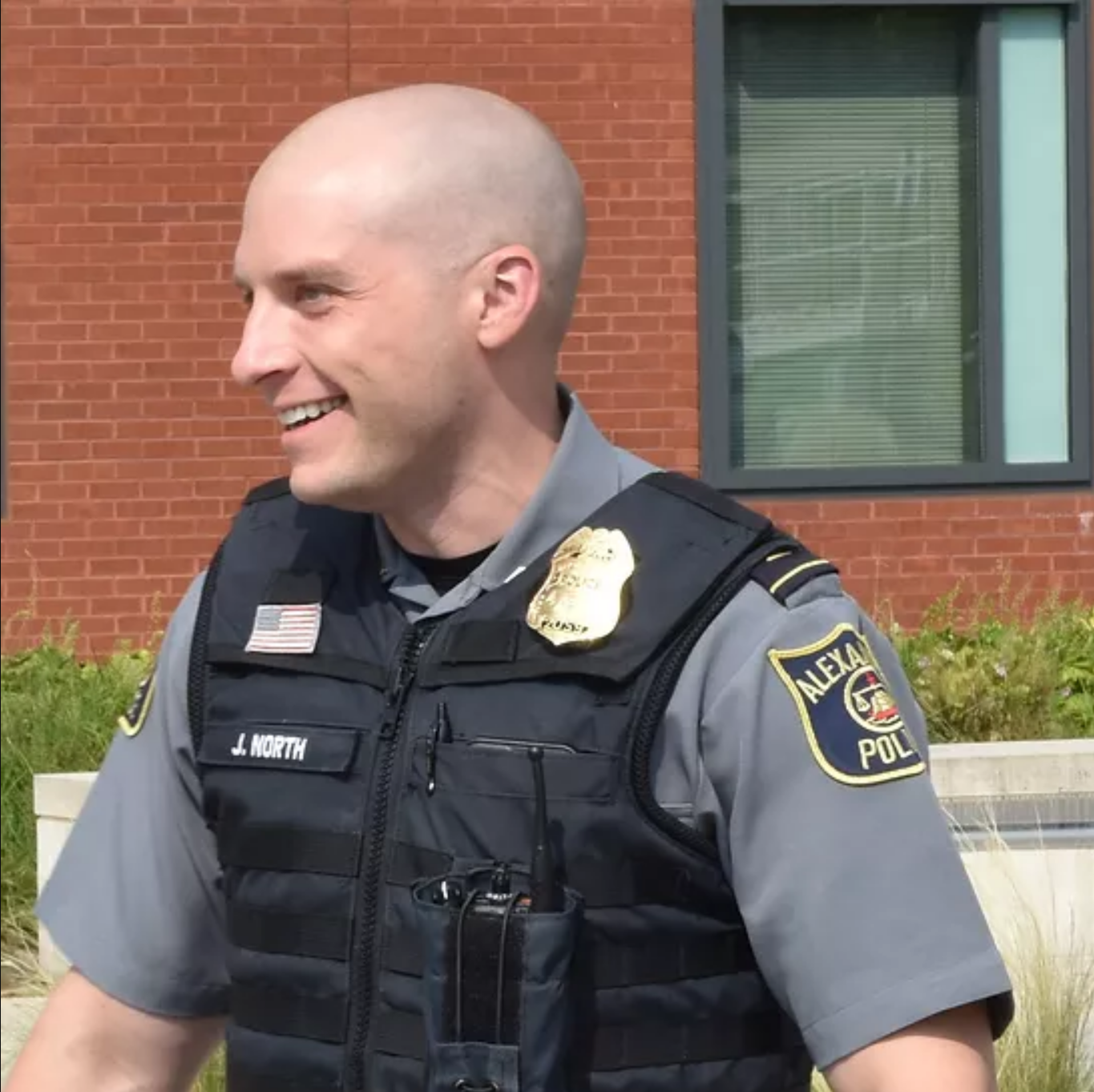 North wearing a vest and standing in front of a brick building