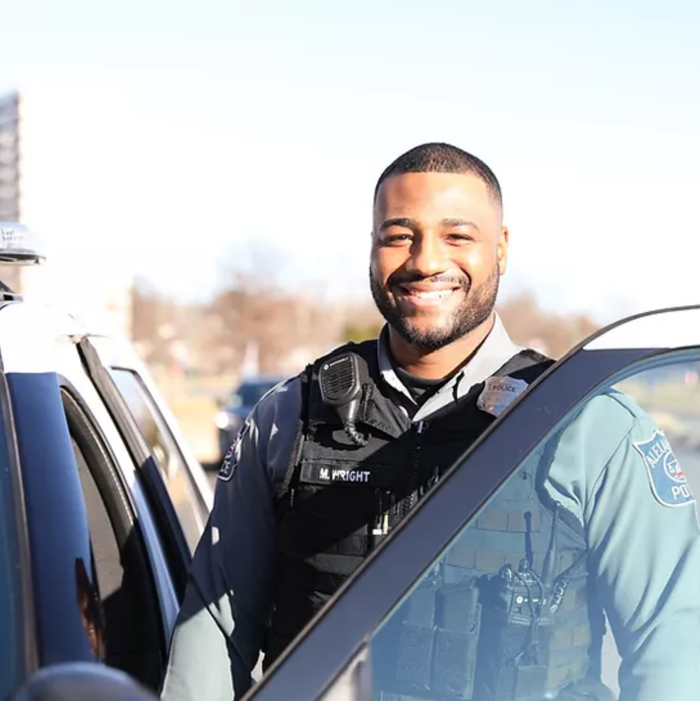 Melvin Wright standing beside the open driver's door of a police car