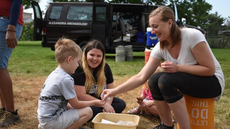 An archaeology intern shows artifacts to children during a family program at the Shuter's Hill site.