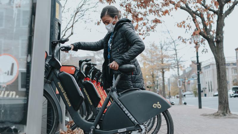 A person renting a Capital Bikeshare bike from a corrall in Alexandria