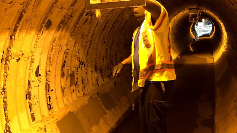 Person performs maintenance inside of a large pipe