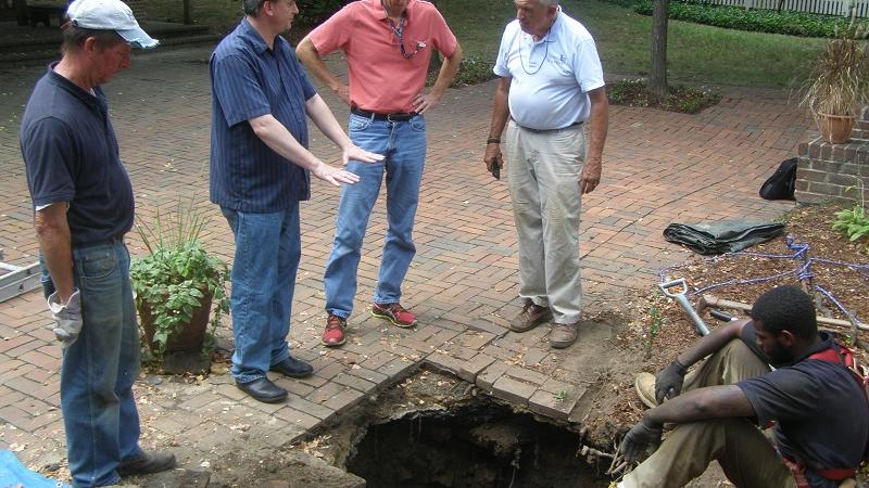 Archaeologist inspects sink hole.