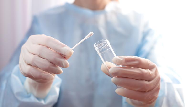 gloved medical professional holds swab for testing