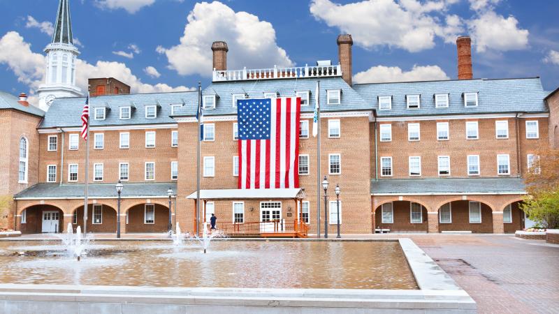 Market Square with the fountain in the foreground and City Hall in the background. A large American flag is hanging over the front entrance of City Hall