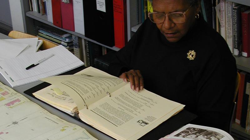 A researcher looks over maps and books.