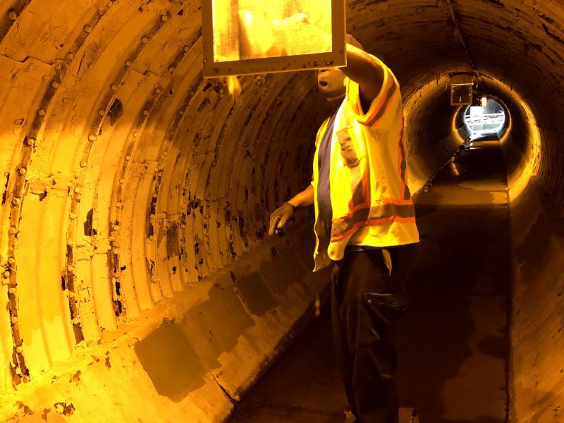 Person performs maintenance inside of a large pipe