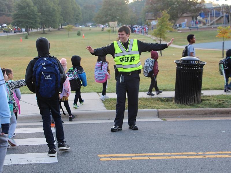 sheriff directing traffic with kids in crosswalk