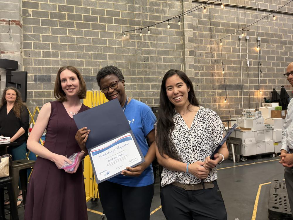 An MRC Volunteer, Anita, smiles with her certificate