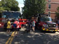 Adults and children stand near a parked Alexandria fire truck and ambulance.