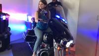 civilian sitting on a Sheriff's motorcycle with deputy in background