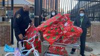 deputy and two civilians with child's bicycle and large holiday gift bags