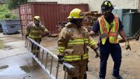 Community Fire Academy participants carry a ladder with the guidance of a first responder during a hands-on session at AFD's training facility.