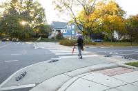 A pedestrian crosses Commonwealth Ave utilizing an upgraded high-visibility crosswalk.