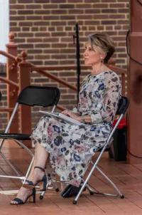 Woman in flowered dress sitting on stage