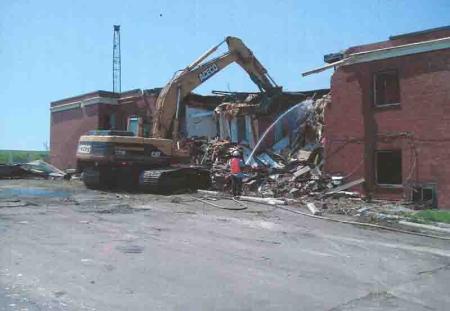 heavy machinery demolishing two-story brick building