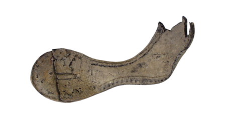 A leather shoe sole that has not been conserved appears lighter and shows significant cracks in the material.